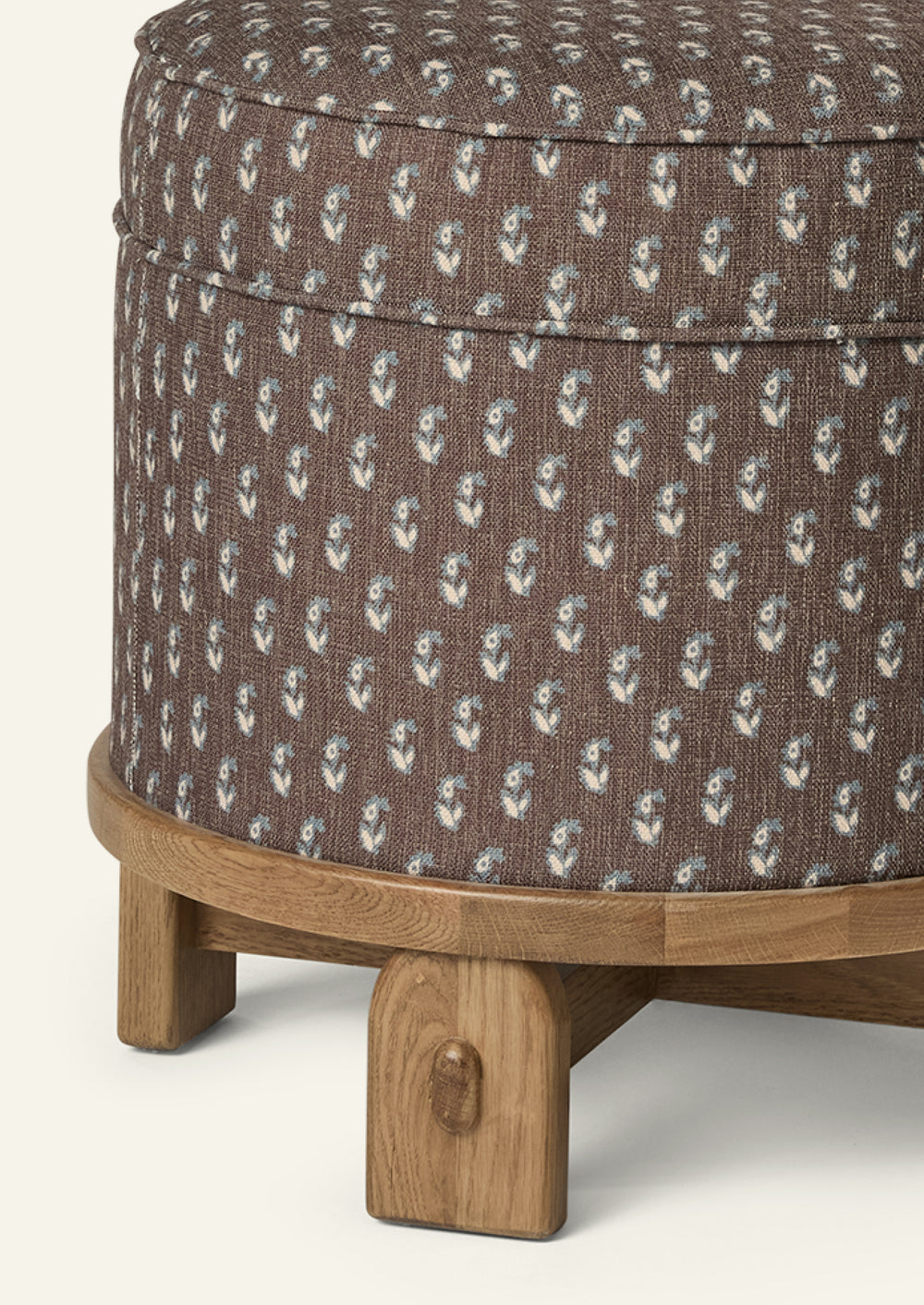 Close-up of the Yara Pouf showing the Cocoa Floral fabric pattern and handcrafted honey oak base. The textured woven upholstery and rounded wood edge highlight the pouf’s artisanal details