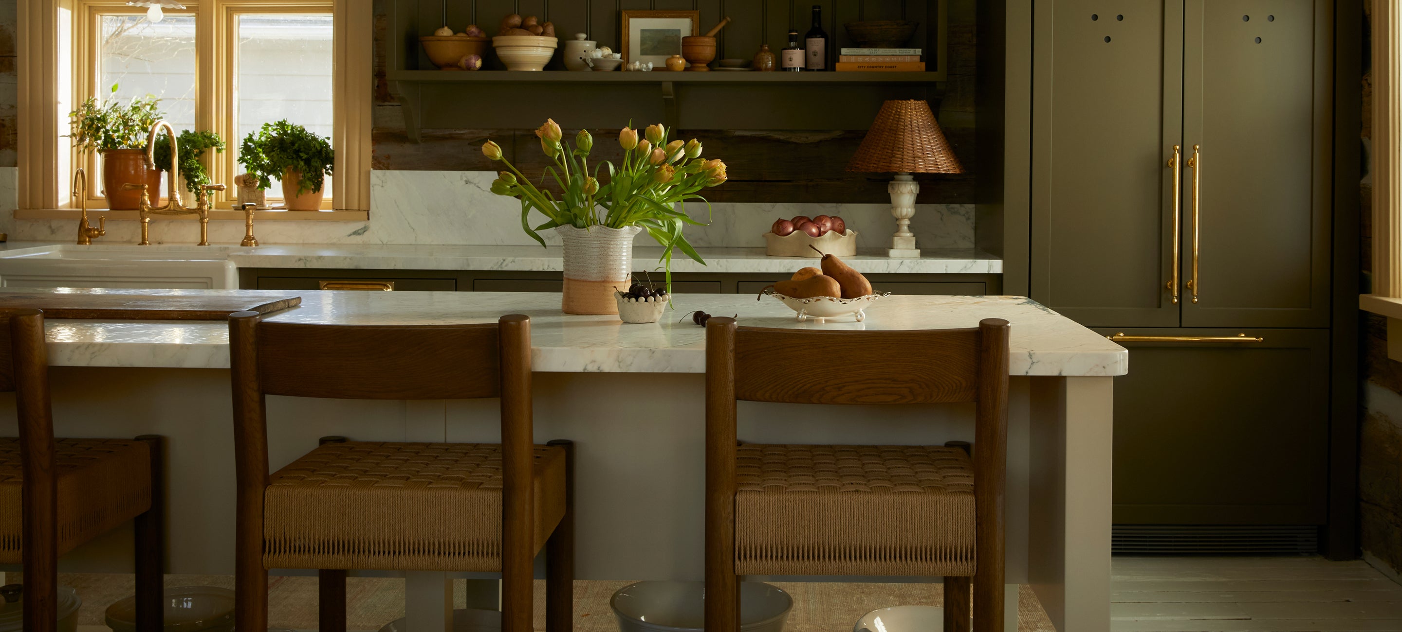 Modern kitchen with marble island, wooden chairs, and decorative elements.
