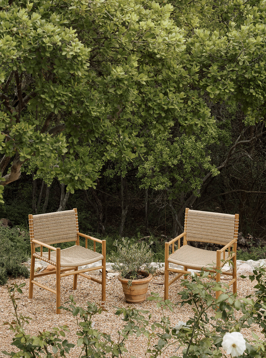 Two Ema chairs with woven seats and backrests in a garden setting.
