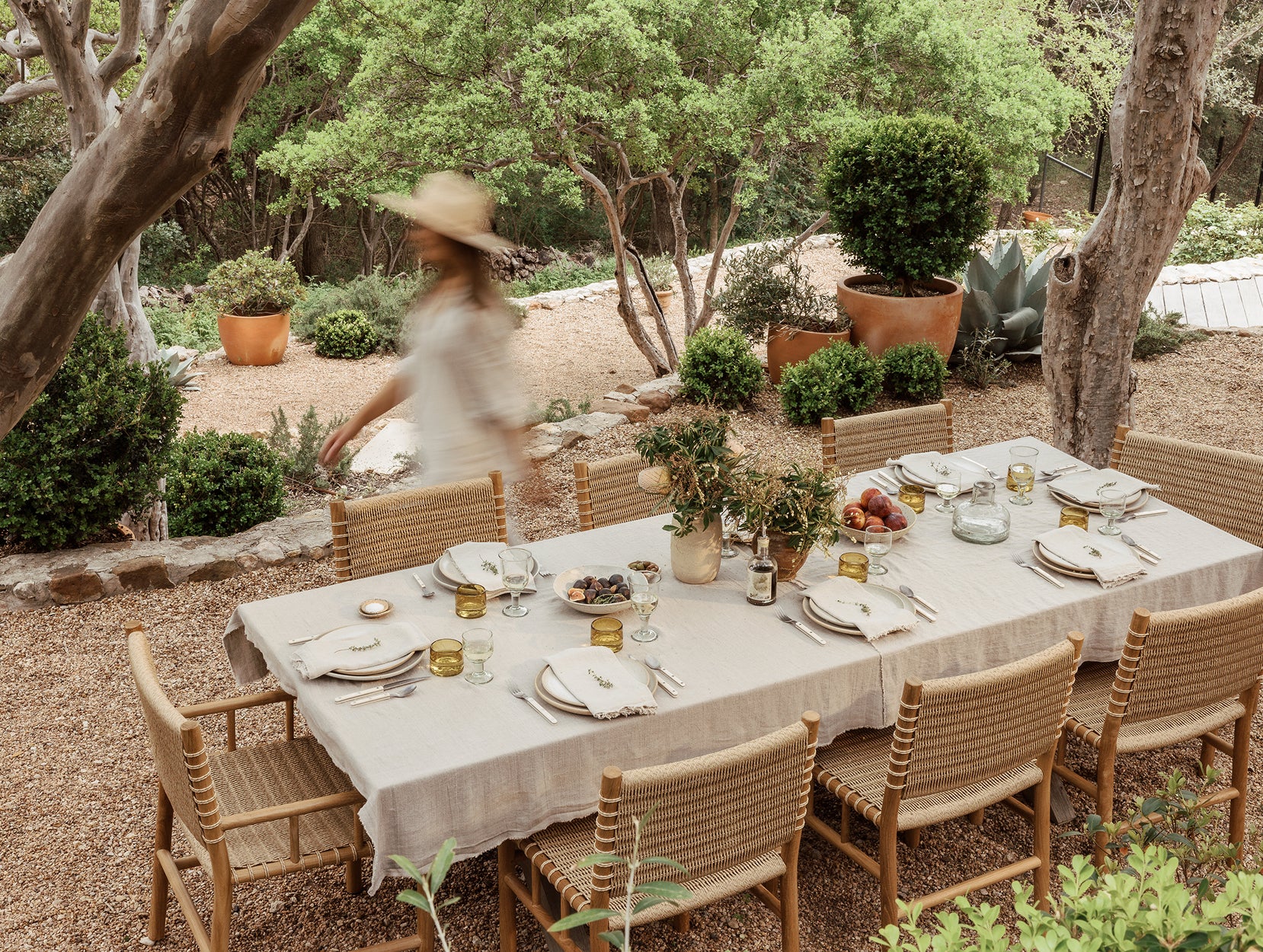 Outdoor dining setup with a table, Ema chairs, and a person in a hat walking by.