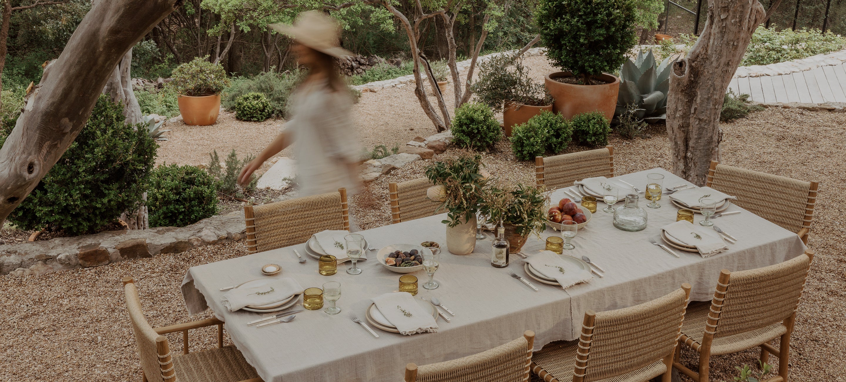 Dining table set for a meal outdoors with a person in the background.