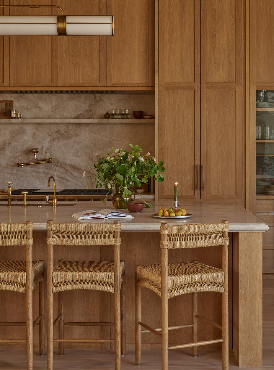 Modern kitchen with wooden cabinets, marble countertop, and suma counter stools.