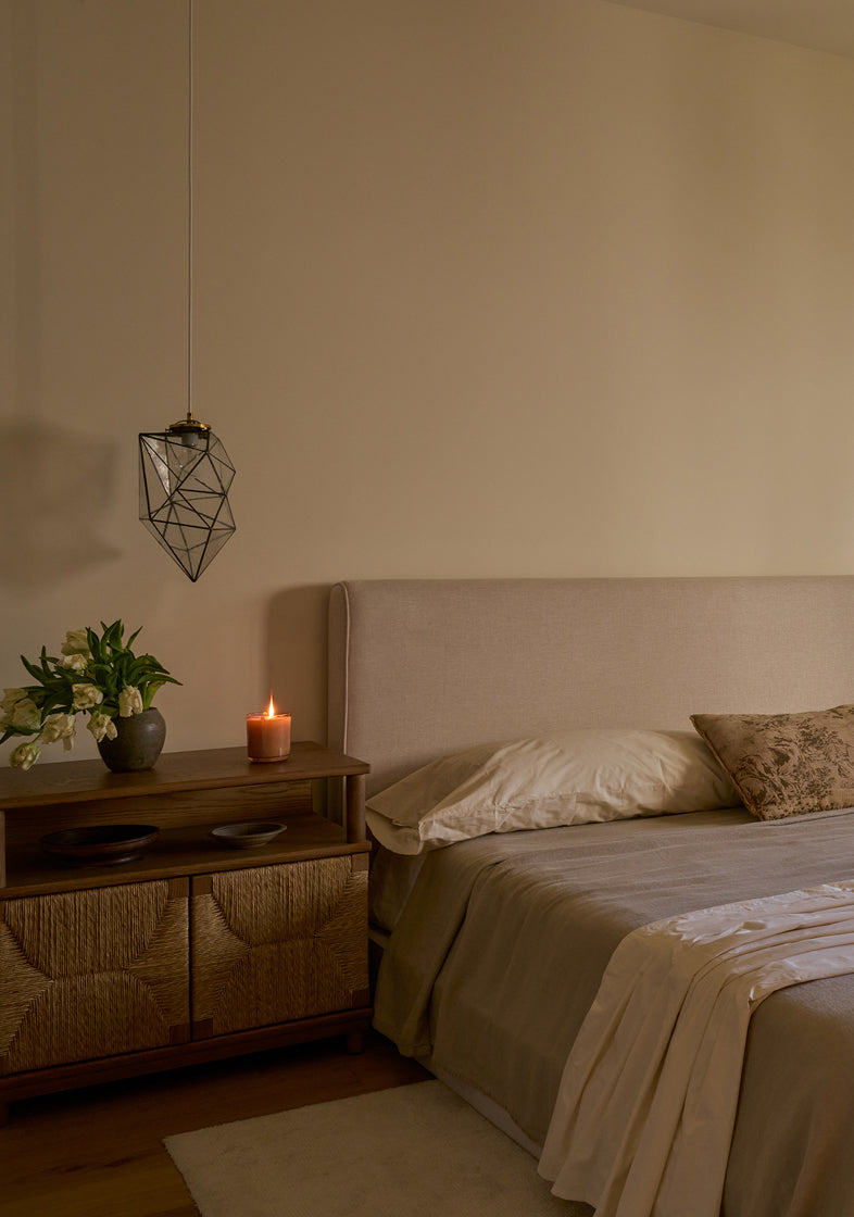 Bedroom with a bed, side table, and hanging light fixture.