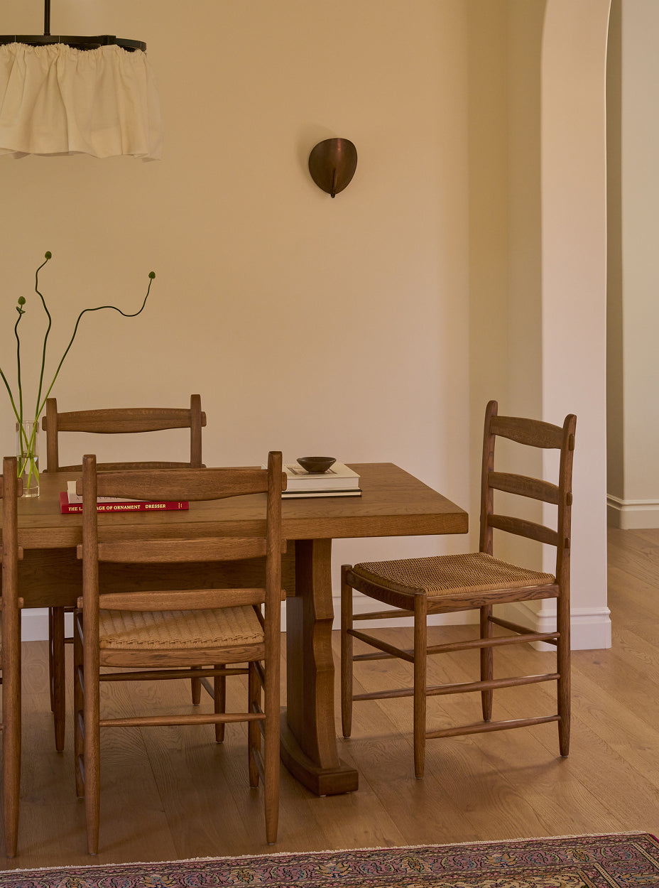 Etta dining table with Tiga chairs in a room with beige walls and wooden floor.