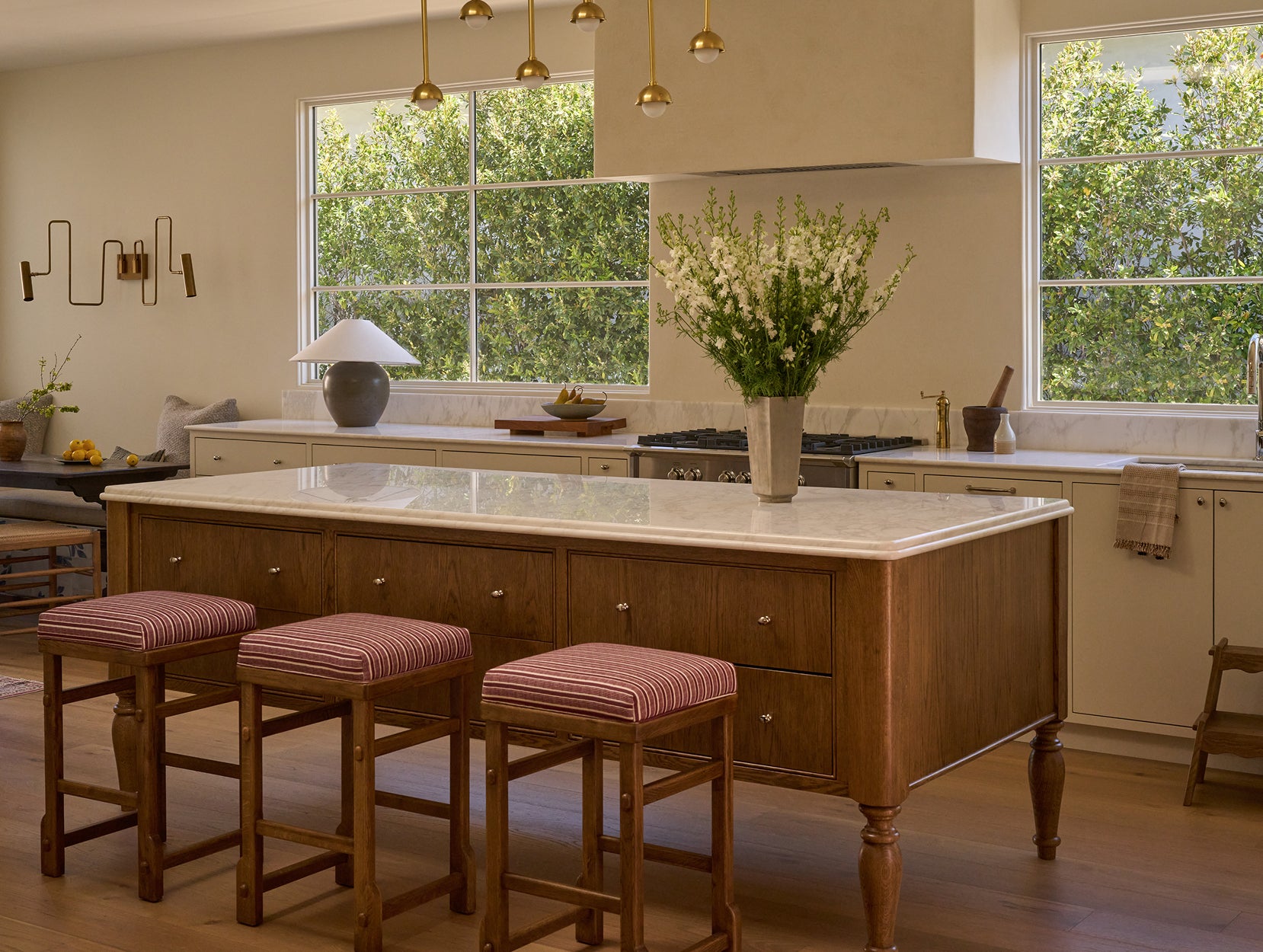 Modern kitchen with wooden island, Sari counter stools, and large windows.