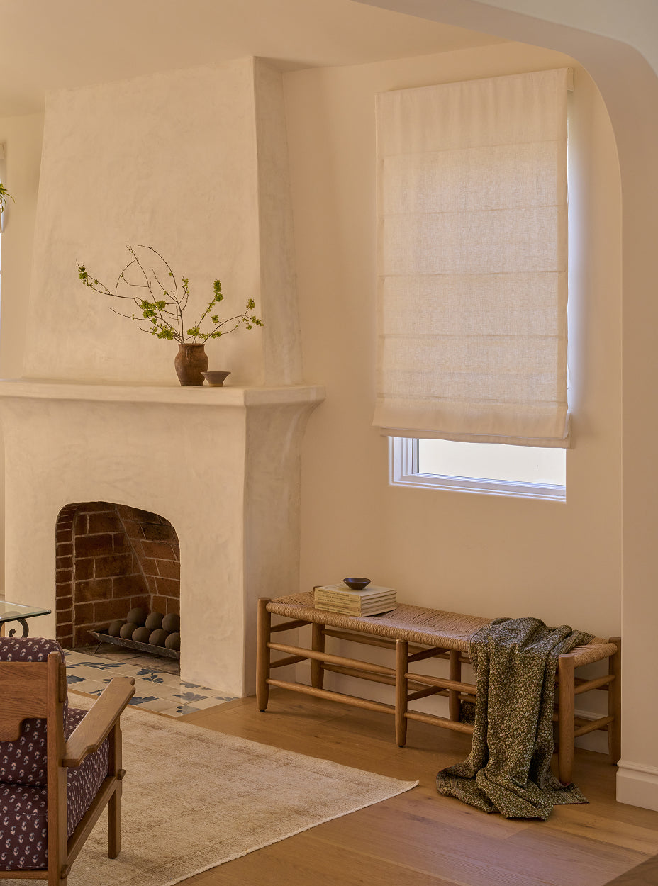 Living room with a fireplace, mina bench, and window with blinds.