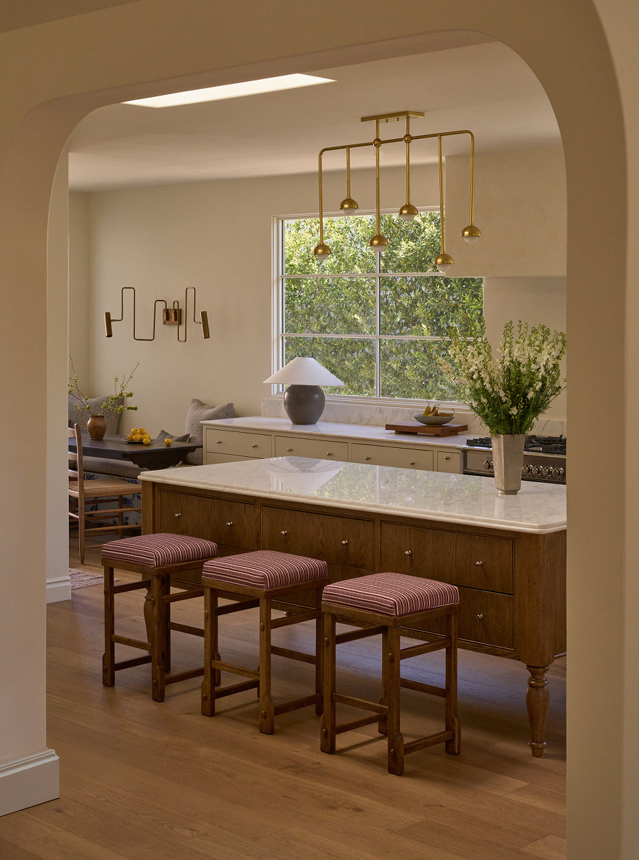 Kitchen with wooden island and yara counter stools, large window, and decorative elements.