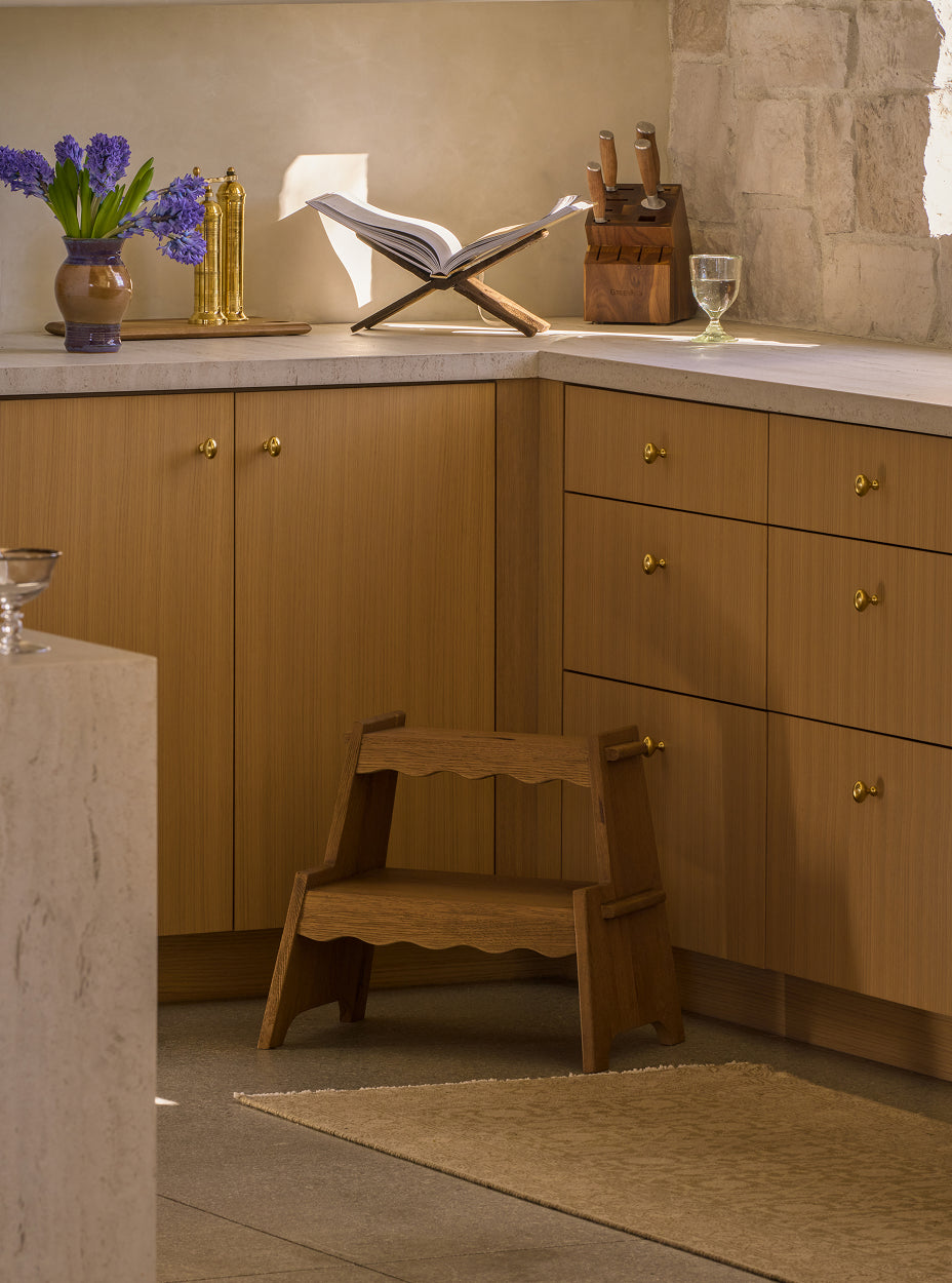 The margot step stool in a kitchen setting with cabinets and decorative items.