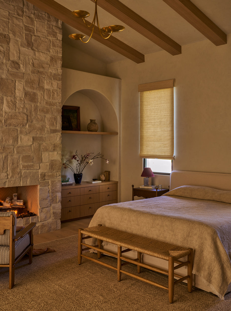 Cozy bedroom with stone fireplace, bed, and the mina bench.