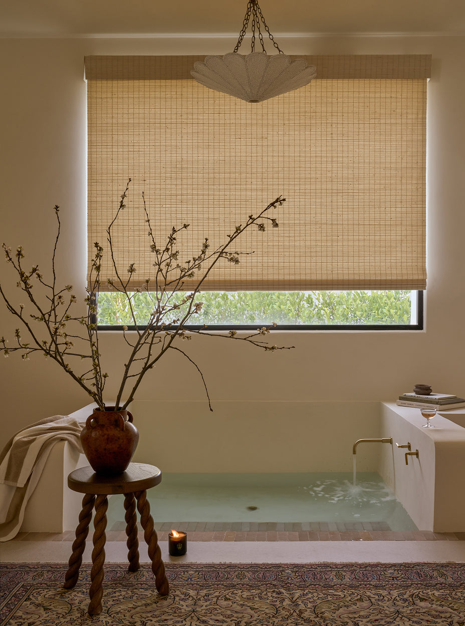Bathroom with a bathtub, woven blind, the twist side table, and decorative elements.