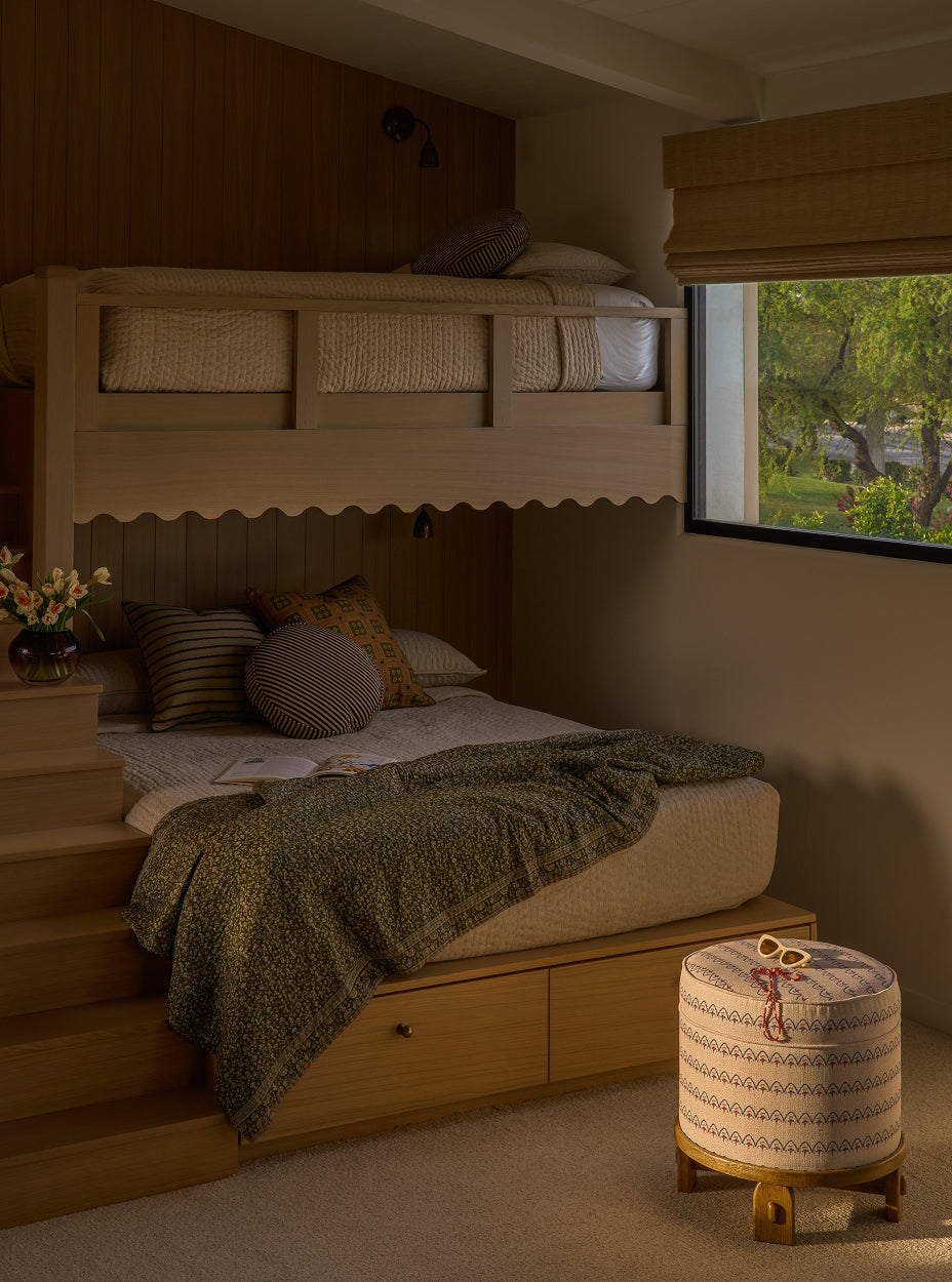 Bunk bed in a room with a window showing greenery outside with the yara pouf.