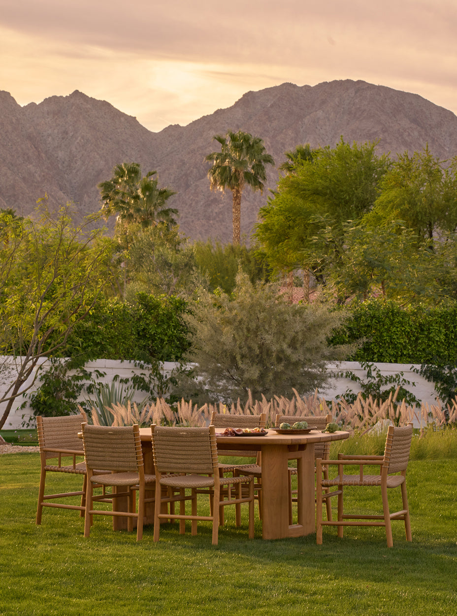 Outdoor dining setup with the ema dining chairs and the hollis dining table in a scenic landscape with mountains and trees.