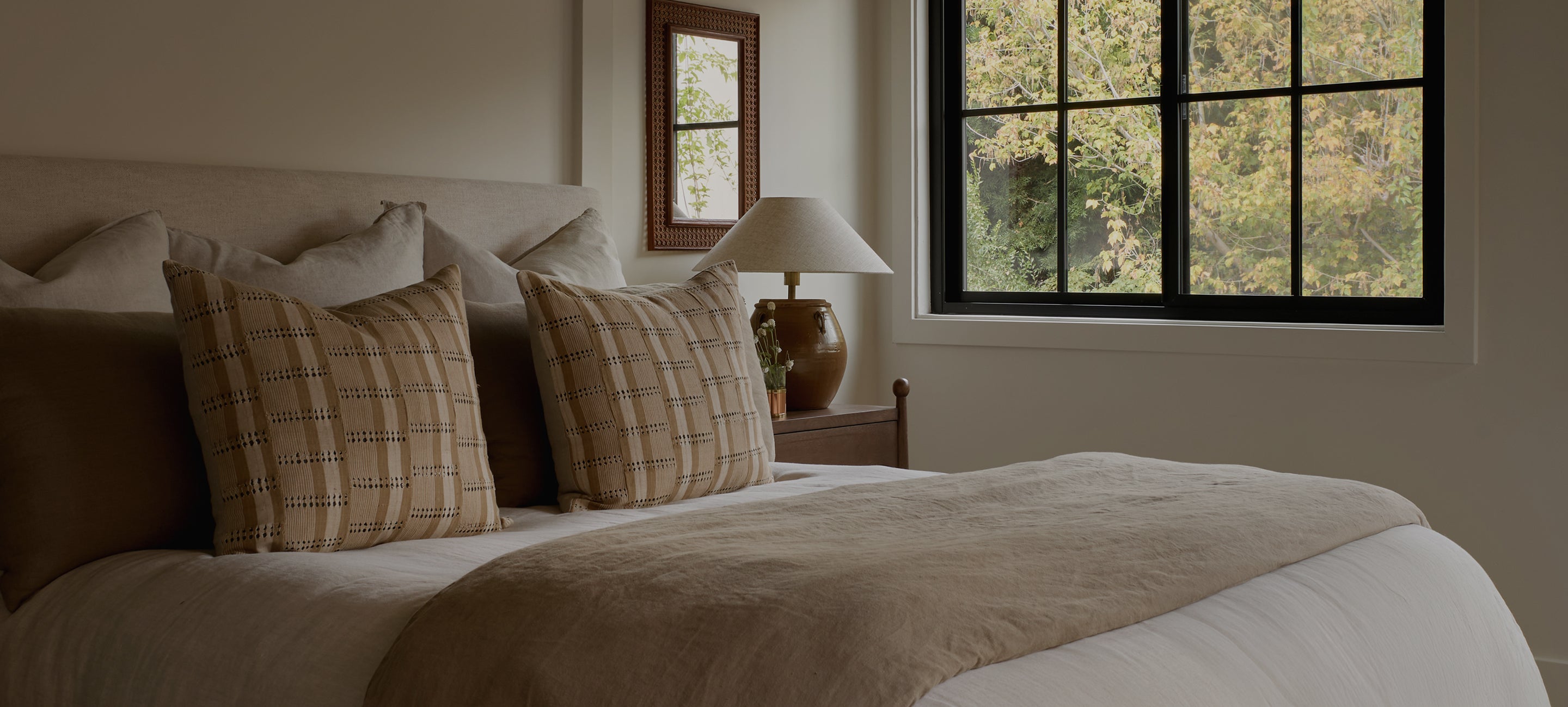 Bedroom with a bed featuring plaid pillows and a lamp on a nightstand.