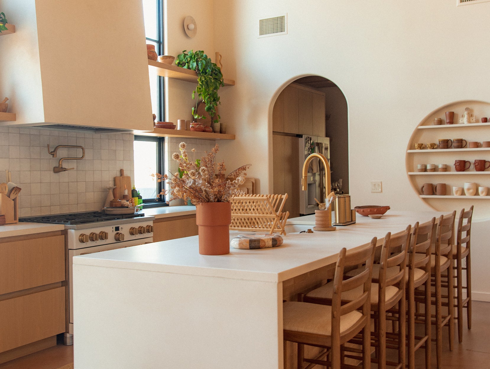 Modern kitchen with white island, Tiga chairs, and decorative elements.