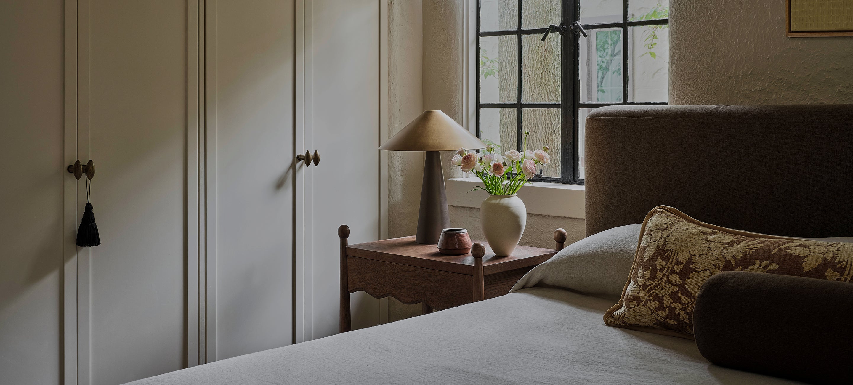 Bedroom with a bed, wave nightstand, and lamp near a window.