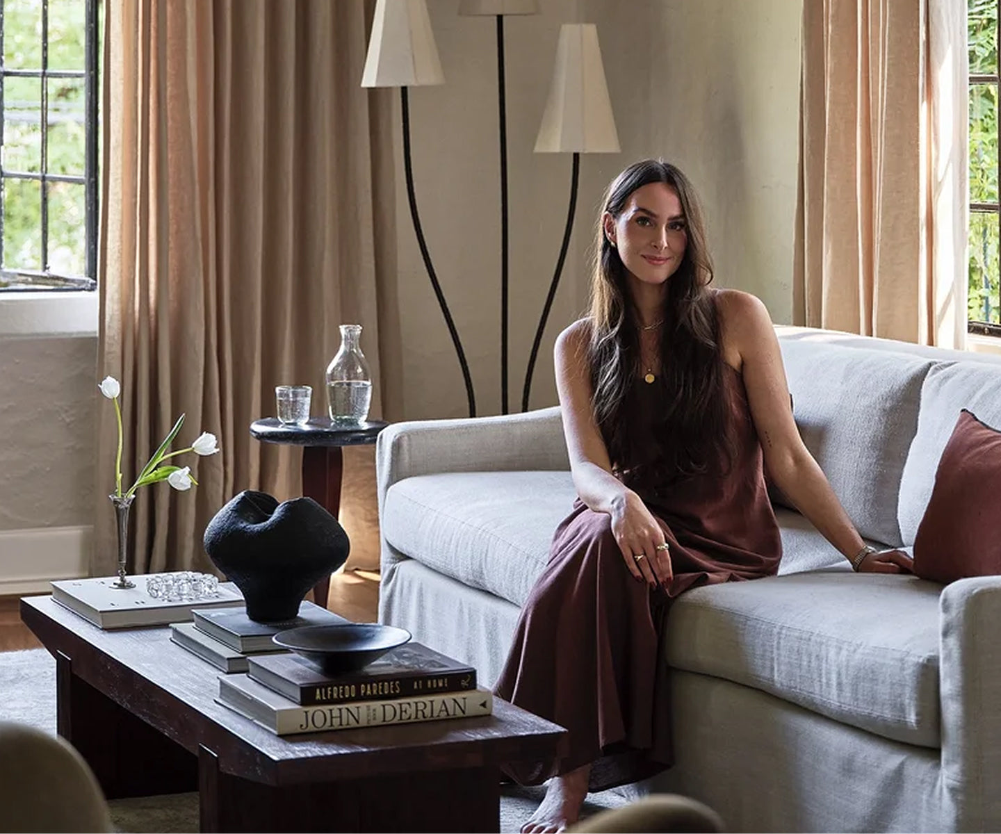 Nicole Arruda sitting on a couch in a stylish living room with decor elements.