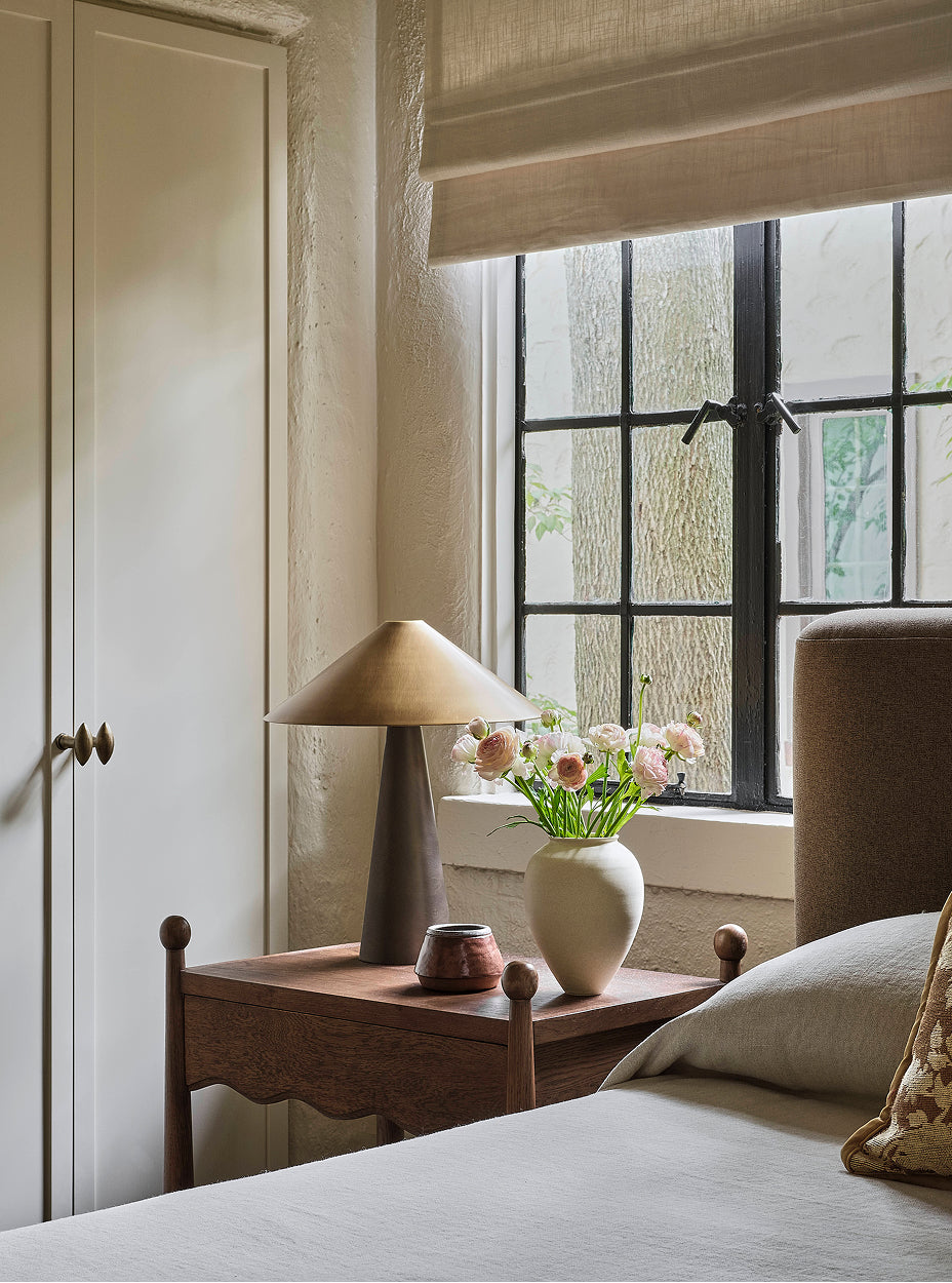 Bedroom with a bed, wave nightstand, and lamp near a window.
