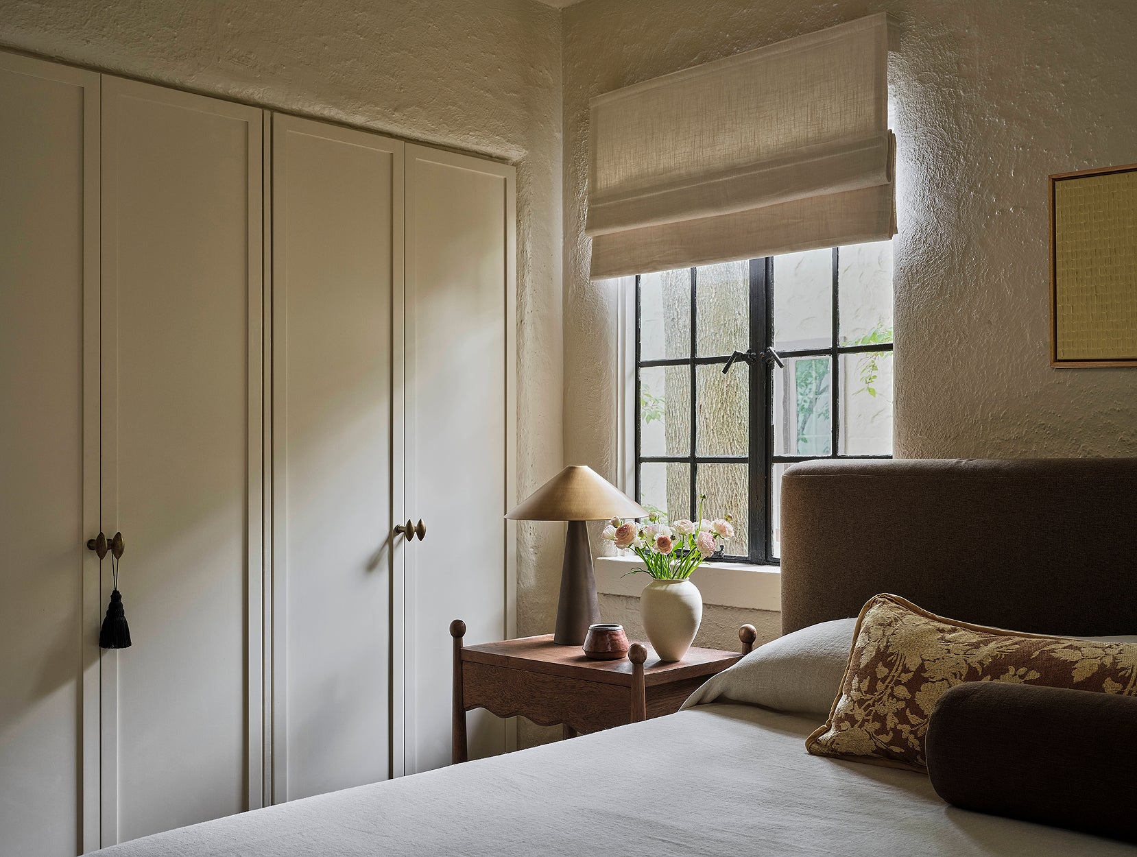 Bedroom with white wardrobes, a bed with pillows, and a lamp on Wave nightstand.