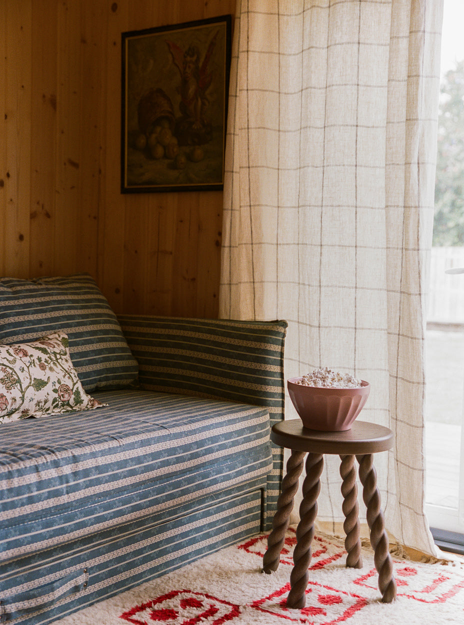 Living room with striped sofa, twist side table, and window with curtains