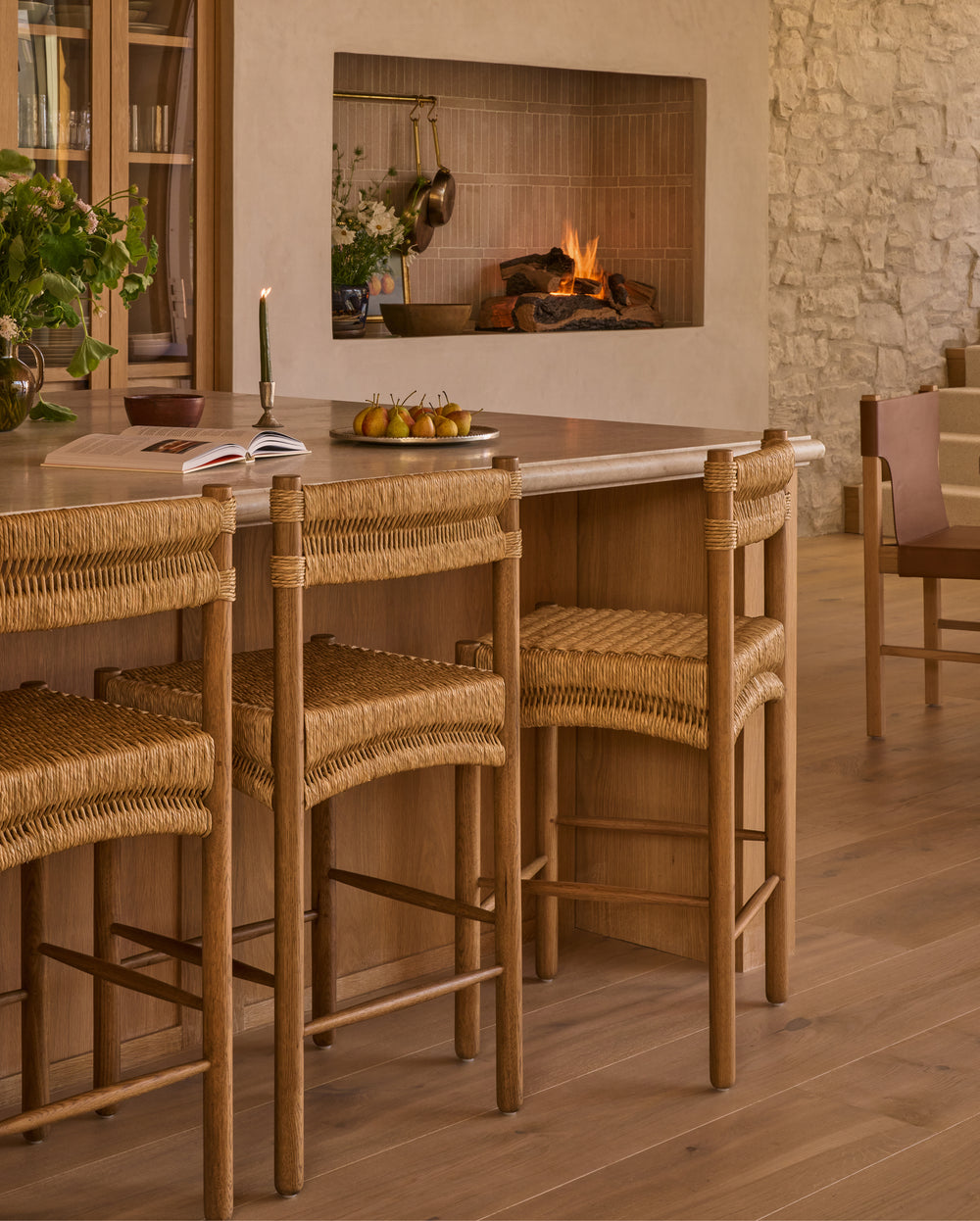 Dining area with wooden table and chairs in front of a fireplace.